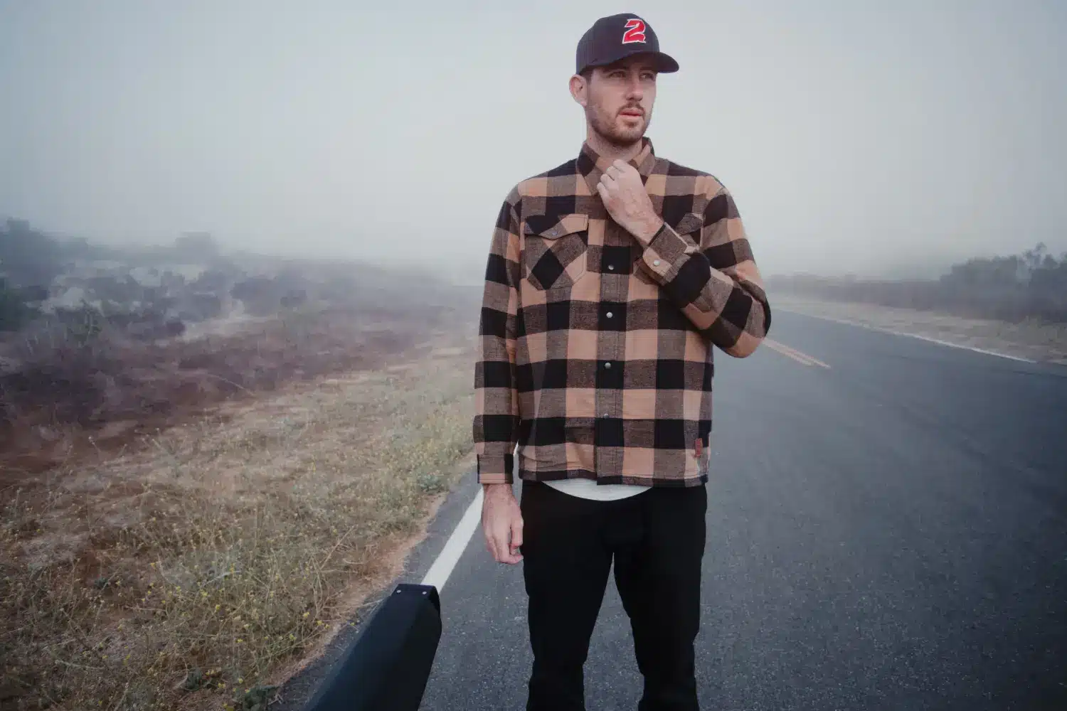 man wearing flannel shirt standing on road