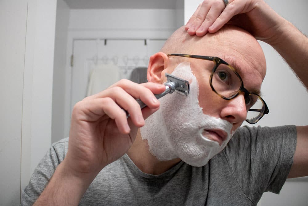man with shaving cream on face shaving