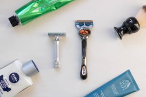 safety and cartridge razor next to one another surrounded by grooming products