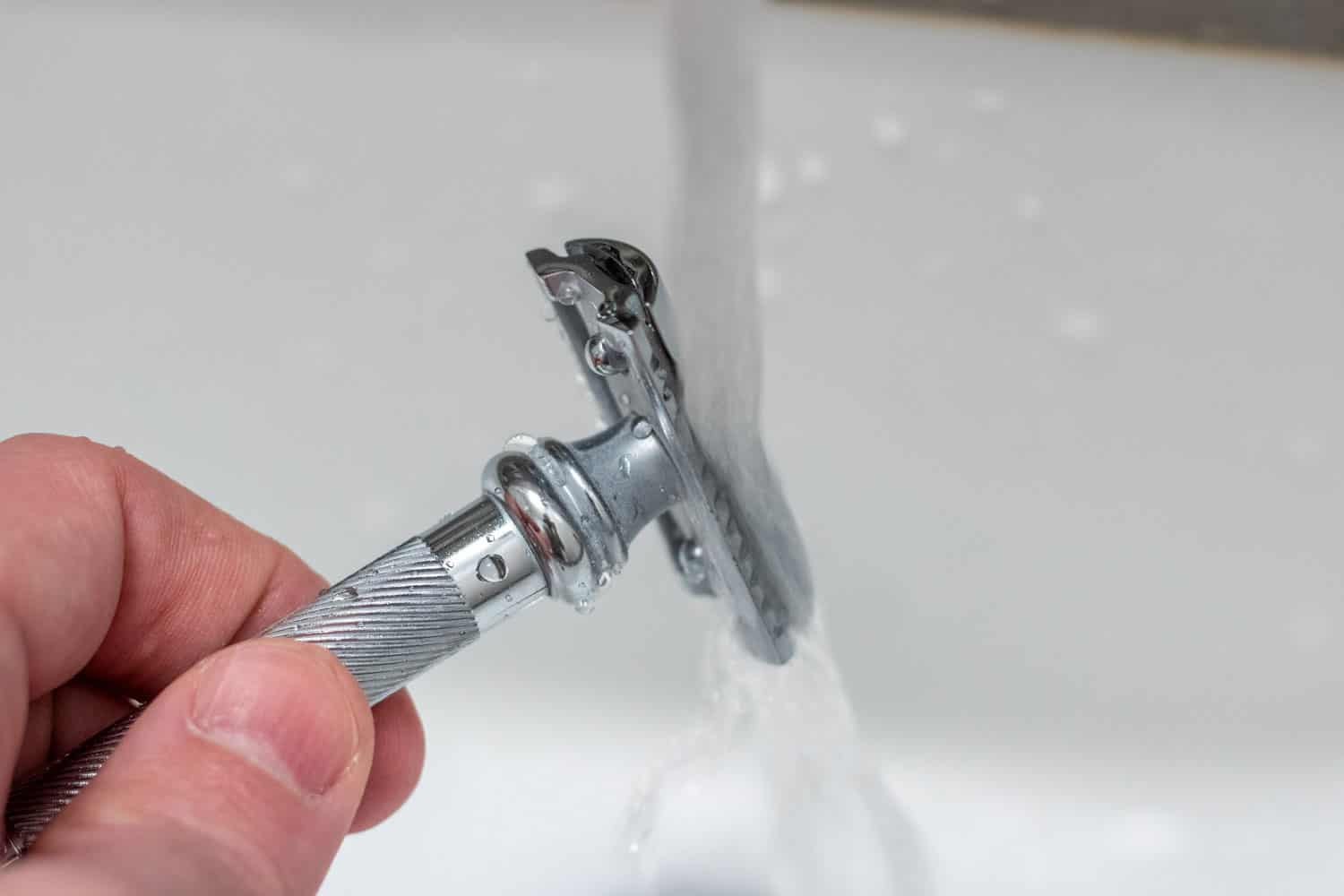 safety razor being rinsed under running water