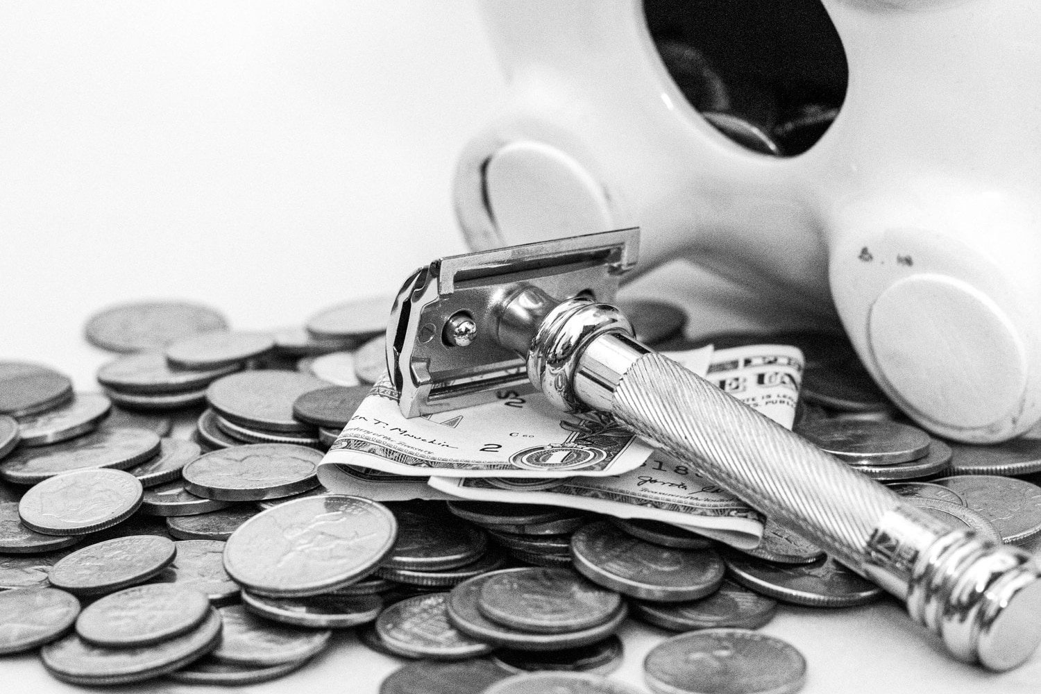 safety razor on top of money with piggy bank in background