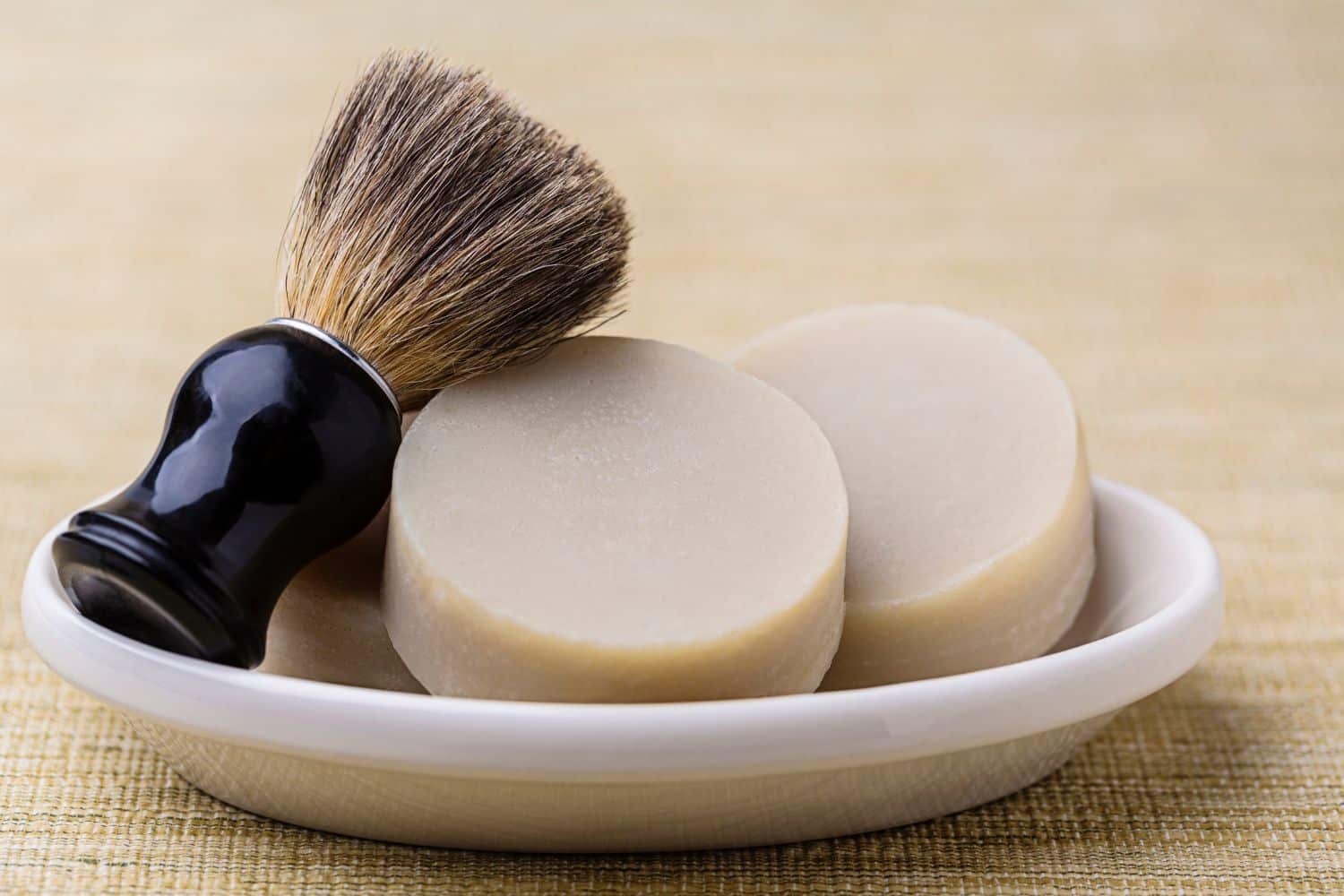 shaving brush and two soap discs on a tray