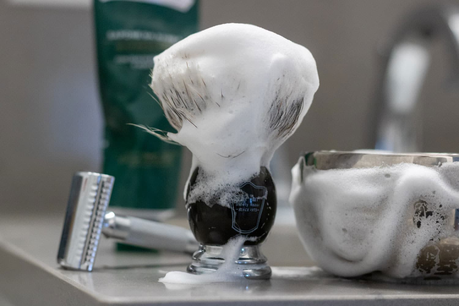 shaving brush with shaving bowl and razor on bathroom countertop