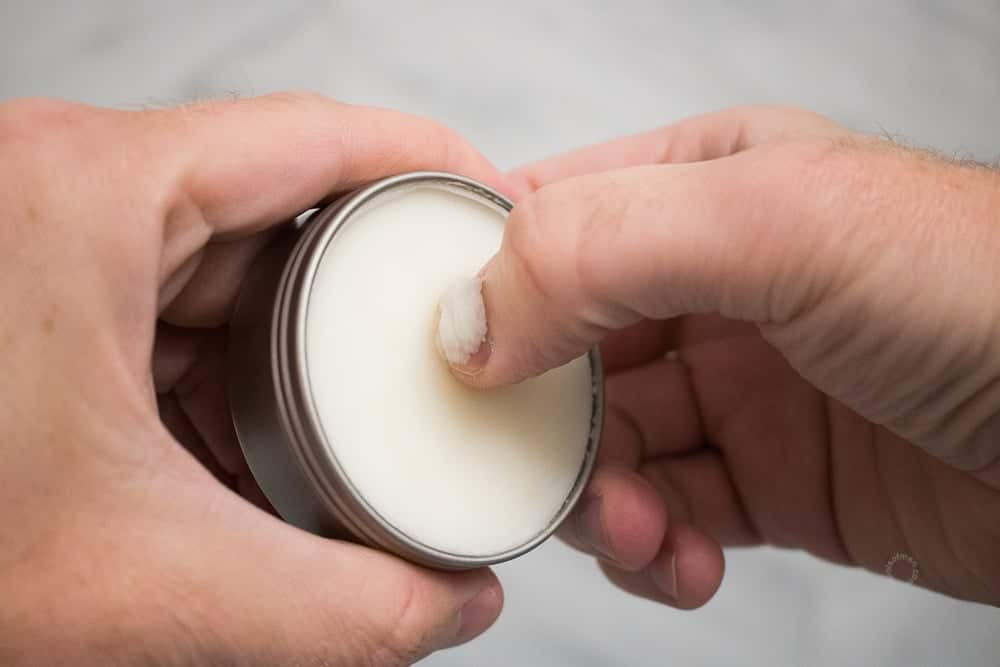 thumb scooping balm out of a tin