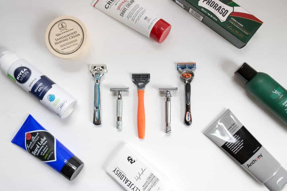 various razors sitting on white paper with decorative grooming supplies around them