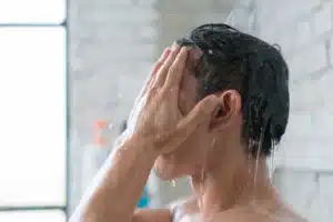 man washing face in the shower
