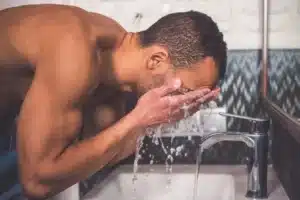 man washing face under water