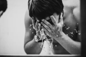 black and white photo of man splashing water on face